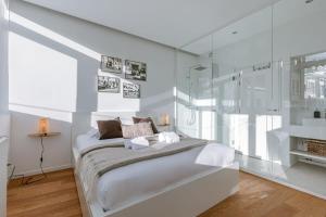 a white bedroom with a bed and a glass wall at Bright apartment overlooking the 3 towers of Ghent in Ghent