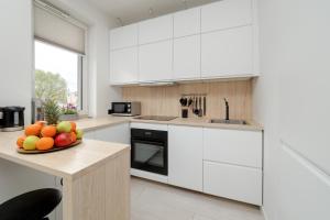 a kitchen with white cabinets and a bowl of fruit on a counter at Bright Apartment with Balcony Close to the Poniatowski Park Łódź by Renters in Łódź