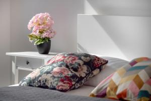 a bed with a pillow and a vase of flowers on a table at Bright Apartment with Balcony Close to the Poniatowski Park Łódź by Renters in Łódź