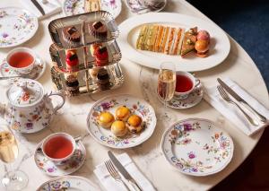 een tafel met borden eten en kopjes thee bij Bulgari Hotel London in Londen