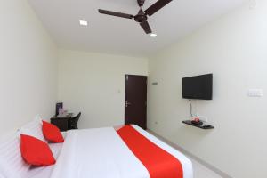 a bedroom with a bed with red pillows and a flat screen tv at Perfect Stay Near Meenambakkam Metro Station in Chennai