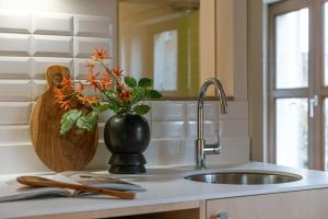 a kitchen counter with a sink and a vase with flowers at Characterful apartment for two in central Ghent in Ghent