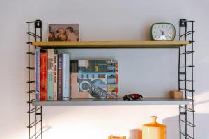 a shelf with books and a clock on it at Characterful apartment for two in central Ghent in Ghent