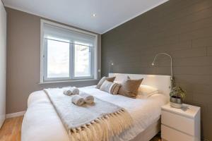 a bedroom with a large white bed with a window at Huswell - Modern apartment in heart of Knokke with terrace in Knokke-Heist