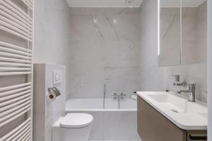 a white bathroom with a tub and a toilet and a sink at Huswell - Modern apartment in heart of Knokke with terrace in Knokke-Heist +29 photos