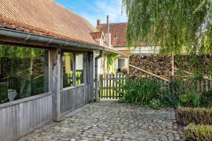 una casa con una valla y una pasarela de piedra en Authentic vacation home 'De Blauwe Kroon', en Oostkamp