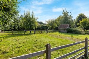 a field with a fence and an old barn at Casiola - Authentic vacation home 'De Blauwe Kroon' in Oostkamp
