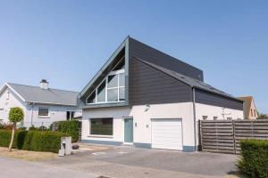 a large white house with a black roof at Spacious house with garden and parking in Blankenberge