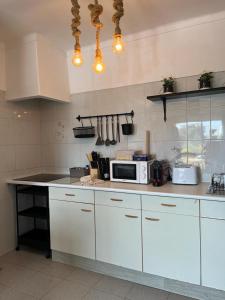 a kitchen with white cabinets and a microwave on a counter at Jupiter Sweet Apartments - Algarve - Praia Vale centeanes in Lagoa