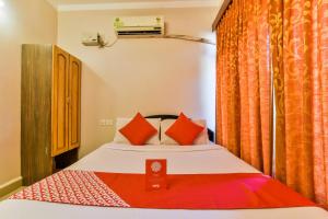 een slaapkamer met een bed met oranje gordijnen bij Hotel Pillar'S Near Immaculate Conception Church in Oud Goa