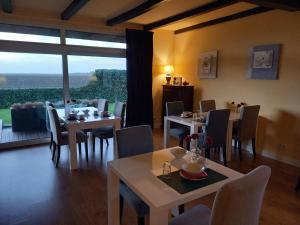 une salle à manger avec des tables et des chaises ainsi qu'une grande fenêtre dans l'établissement Bed & Breakfast Rheiderland, à Ditzumerverlaat