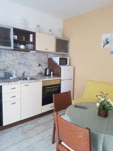 uma cozinha com uma mesa e uma cozinha com um lavatório em Къща за гости Ани em Černomorec