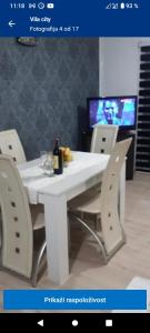 un tavolo bianco con sedie e una bottiglia di vino sopra di Vila City a Bijeljina