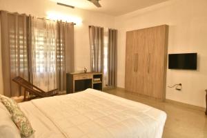 a bedroom with a bed and a desk and a television at Gloria Homestay ,Thrissur in Trichūr