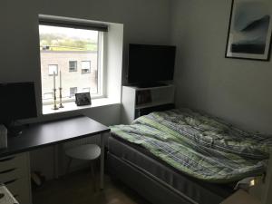 a bedroom with a bed and a desk and a window at Stor lejlighed tæt på Århus C. Stor tagterrasse in Aarhus