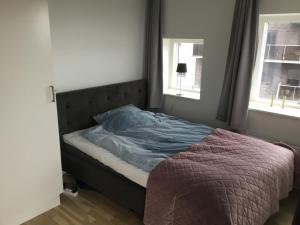 uma cama num quarto com duas janelas em Stor lejlighed tæt på Århus C. Stor tagterrasse em Aarhus