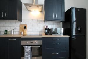 a kitchen with black cabinets and a stove and a microwave at Superb One Bedroom Apartment in Dundee in Dundee