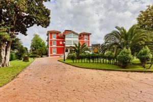 una casa rossa con alberi e un vialetto in mattoni di Silken Spa La Hacienda De Don Juan a Llanes