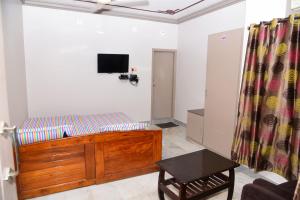 een woonkamer met een bed en een televisie bij Varsha Residency 