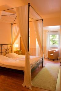 a bedroom with a canopy bed and a chair at Hotel Grüner Jäger in Jesteburg