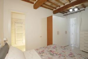 a white bedroom with a bed and a window at La Casa nel Borgo Medievale (Lago di Trasimeno) in Passignano sul Trasimeno +7 photos