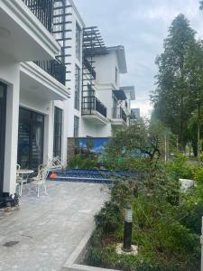 a white building with a patio with a table and chairs at Resort Xanh Villa 5 Stars in Nam Giao