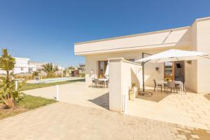 ein weißes Haus mit einem Sonnenschirm und einer Terrasse in der Unterkunft Villa Daisy in Caprarica di Lecce
