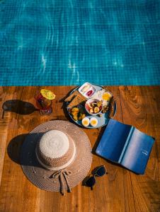 een hoed en een dienblad met eten naast een zwembad bij Villa Karma Pokhara in Pokhara