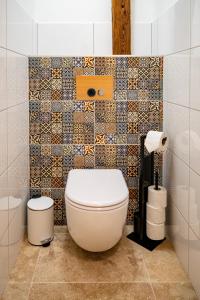 a bathroom with a toilet and a tiled wall at Kníže Ferdinand Apartments in Mikulov