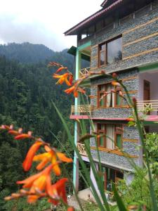 un edificio con fiori arancioni di fronte di The Forest Pinnacle and Café, Jibhi a Jibhi