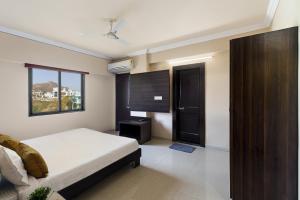 a bedroom with a bed and a window and a door at Lazy Daze by UCH in Udaipur +2 photos