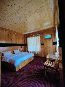 The Forest Pinnacle and Café, Jibhi في Jibhi: غرفة نوم بسرير كبير وسقف خشبي