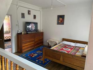 een slaapkamer met een bed, een dressoir en een televisie bij Nimantrana Homestay in Darjeeling