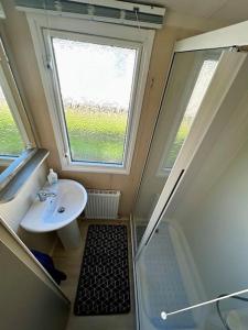 a small bathroom with a sink and a window at Charming Chamber with spacious relaxing area in Pagham