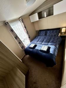 a bedroom with a blue bed and a window at Charming Chamber with spacious relaxing area in Pagham