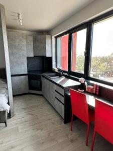 a kitchen with a sink and a table with red chairs at Kate Studio in Galaţi +8 photos