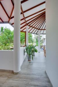 a porch with white columns and a roof with plants at Villa Sunbreeze in Beruwala