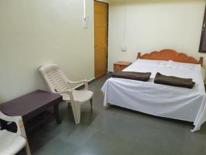 una camera da letto con un grande letto bianco e una sedia di Anand Nivas a Malwan
