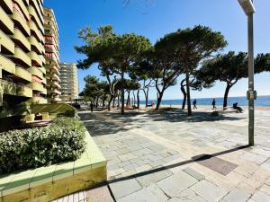 una acera junto a una playa con árboles y un edificio en Apartament mar i vent, en Platja d'Aro