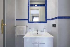 Baño blanco con lavabo y espejo en Loft Tejares de Triana, en Sevilla
