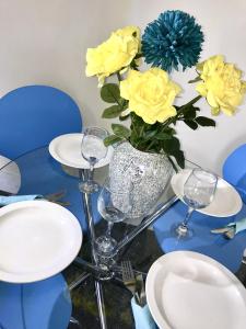 una mesa con gafas y un jarrón con rosas amarillas en Coastal Apartment, en Southend-on-Sea