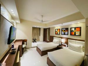 a hotel room with two beds and a flat screen tv at Sangai Continental (The Boutique Hotel) in Imphal
