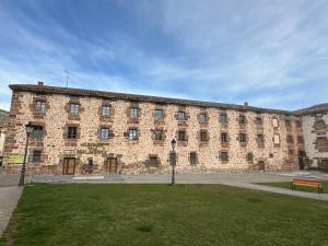 a large brick building with a park in front of it at Albergue Real Fabrica de Ezcaray in Ezcaray