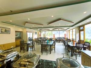 a restaurant with tables and chairs and tables and windows at Hotel Grand Oasis in Manāli