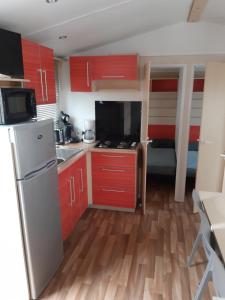 een kleine keuken met rode kasten en een koelkast bij camping le novela in Port-la-Nouvelle