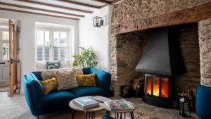 a living room with a blue couch and a fireplace at Gable Cottage in Meysey Hampton