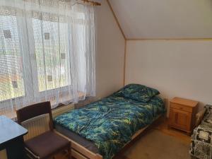 um pequeno quarto com uma cama e uma cadeira em Beskidy em Krosno