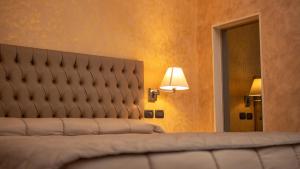 a bedroom with a bed with a headboard and a mirror at Hotel Donna Crescenza in Locorotondo
