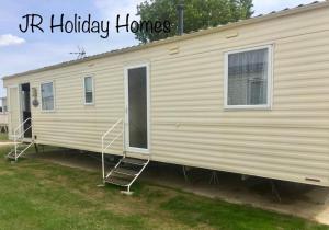 a mobile home with a porch and a ladder on it at J.R. Holiday Homes in Clacton-on-Sea