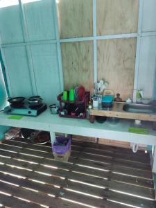 eine Küchentheke mit einer Spüle und einem Tisch mit Geschirr in der Unterkunft Selambak Homestay in Tarempah